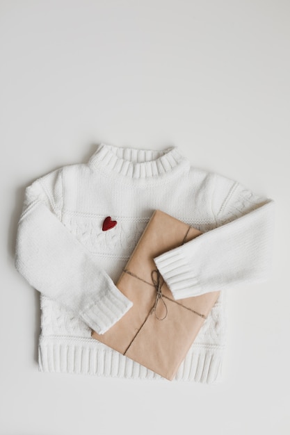 Coeur rouge, un cadeau et un pull en tricot blanc. Concept de préparation de cadeaux de coeur. Mise à plat