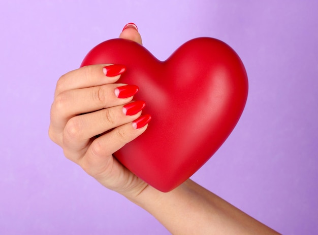 Coeur rouge dans la main de la femme sur fond de couleur