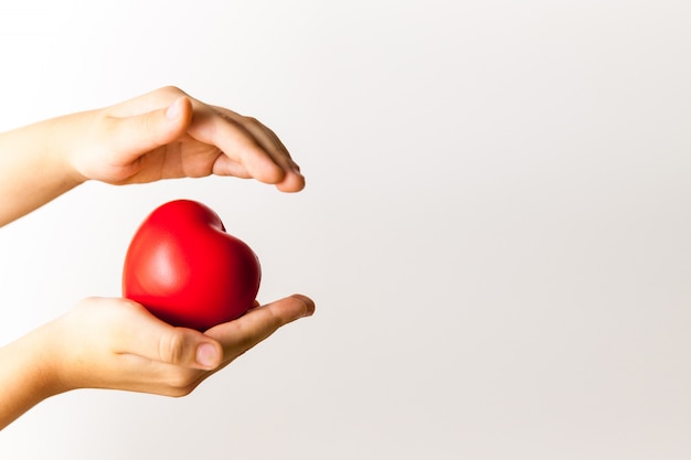 Coeur rouge dans les mains de l'enfant sur fond clair