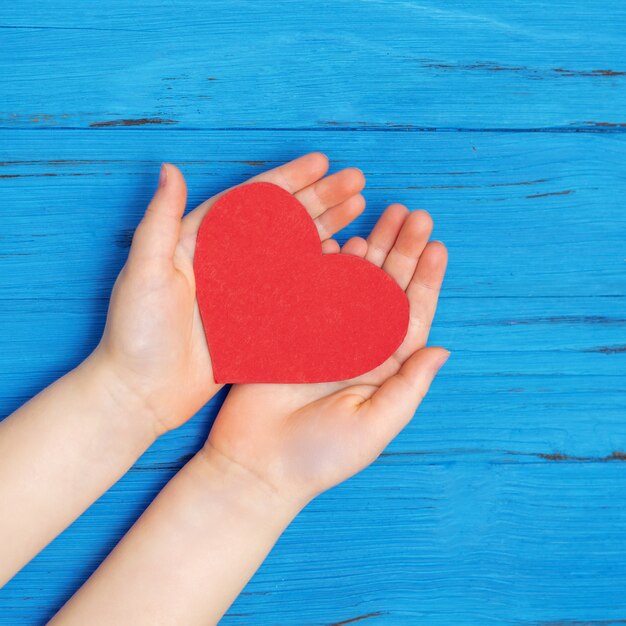 Coeur rouge dans les mains de l'enfant