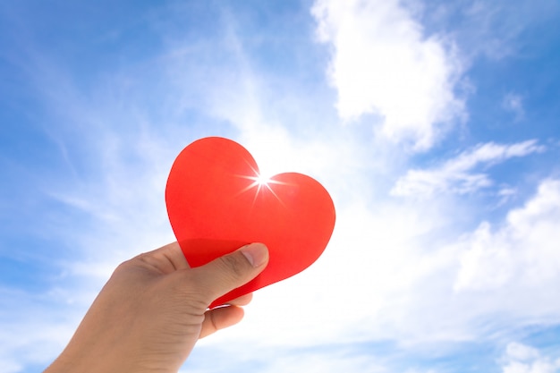 Coeur rouge dans les mains sur fond de ciel