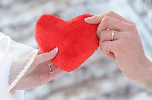 Coeur rouge dans les mains de la mariée et le marié se bouchent