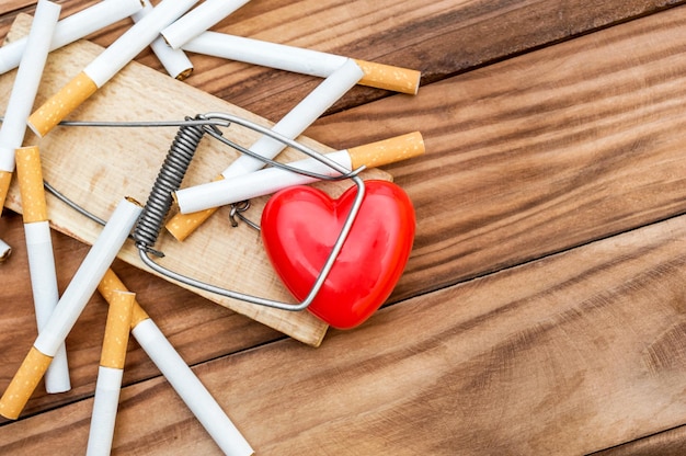 Coeur rouge dans une souricière avec des cigarettes sur le fond en bois Vue de dessus