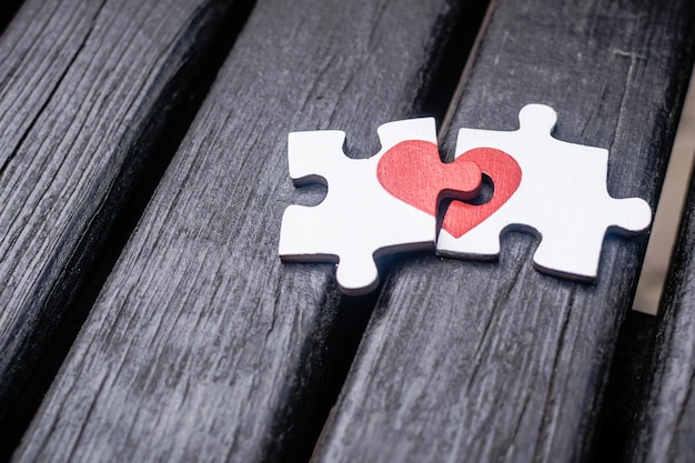 Coeur rouge est dessiné sur les pièces du puzzle en bois se trouvant à côté de l'autre sur fond de bois Love concept St Valentine day