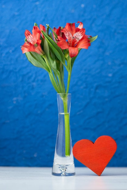 Coeur rouge et fleurs en pot sur bleu