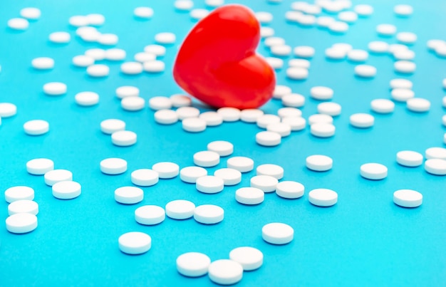 Coeur rouge avec des pilules blanches sur fond médical bleu