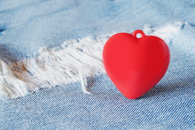 Coeur rouge portant sur le dessus de vieux jeans déchirés. Concept de la Saint-Valentin.