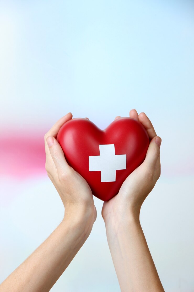 Photo coeur rouge avec signe de croix dans la main féminine, gros plan, sur une surface légère