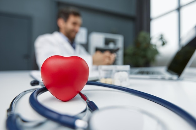 Photo coeur rouge stéthoscope et cardiogramme sur table grise concept de cardiologie