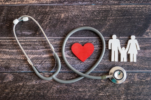 Coeur rouge, stéthoscope et famille d'icônes sur le bureau en bois. Concept d'assurance médicale