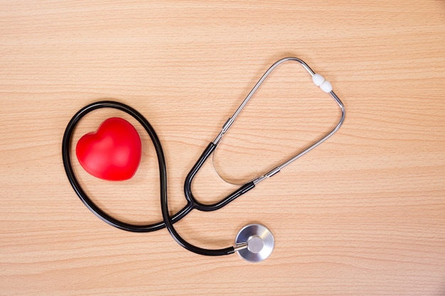 Coeur rouge et stéthoscope sur table en bois. Outil de docteur pour écouter le battement de coeur. Concept de soins de santé.