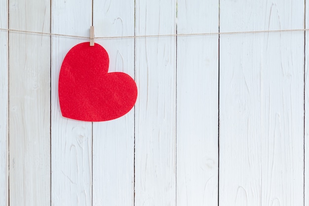 Coeur rouge suspendu sur fond de bois blanc avec espace de copie.