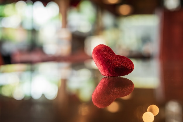 Coeur rouge sur verre avec fond de bokeh de réflexion