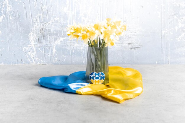 Coeur sous forme de puzzles aux couleurs du drapeau de l'Ukraine avec des fleurs jaunes
