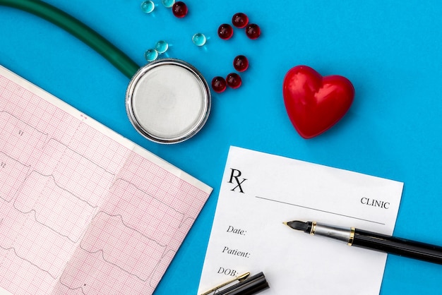 Le cœur, le stéthoscope, le cardiogramme, le reçu de pharmacie et les comprimés sont mis en évidence sur une surface bleue