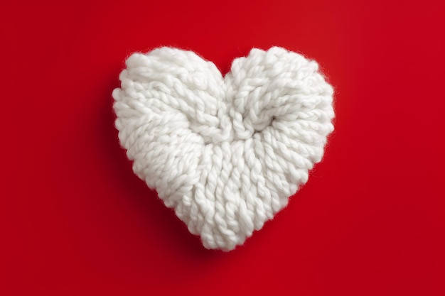 Un coeur tricoté blanc est sur un fond rouge.
