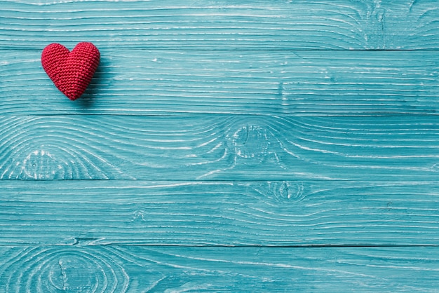 Cœur tricoté sur fond bleu en bois