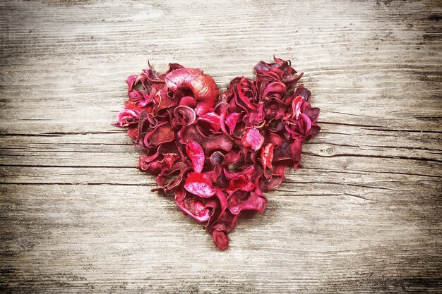 Coeur vintage de pétales secs rouges sur table en bois