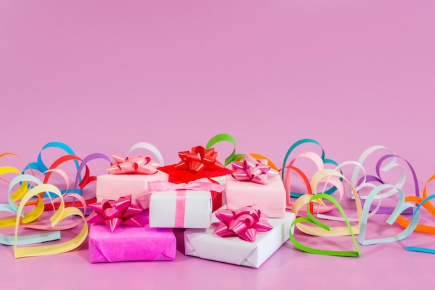 Coeurs d'amour en papier multicolore et cadeaux sur fond rose