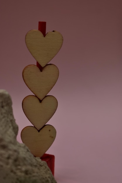 Coeurs en bois sur un rocher avec un fond rose.