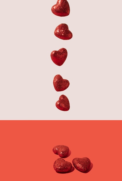 Des cœurs brillants rouges sur un fond rose pastel Concept de la fête de la Saint-Valentin Composition minimale