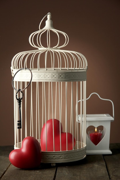 Coeurs en cage décorative sur table en bois, sur fond marron