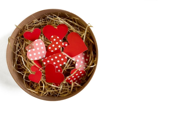 Coeurs découpés dans du papier rouge et pointillé dans un petit panier en bois isolé sur fond blanc