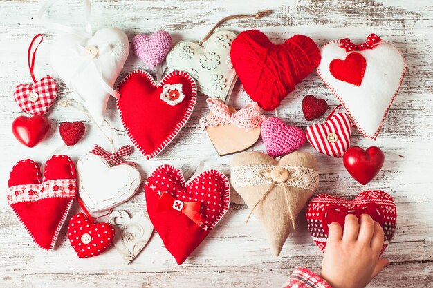 Coeurs faits à la main de Valentine sur la table en bois minable et la main de l'enfant