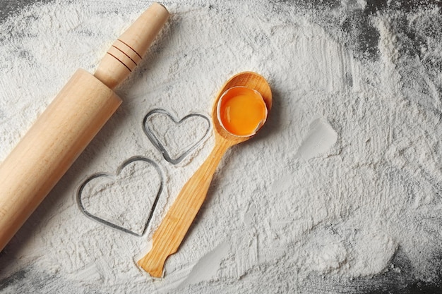 Coeurs de farine et rouleau à pâtisserie, cuillère en bois sur fond gris