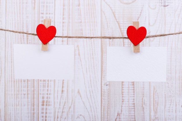 Coeurs en feutre rouge faits à la main et papier blanc suspendu à une corde avec des pinces à linge