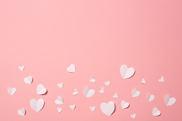 Coeurs de papier blanc sur fond rose. Composition de la Saint-Valentin. Bannière. Mise à plat, vue de dessus.