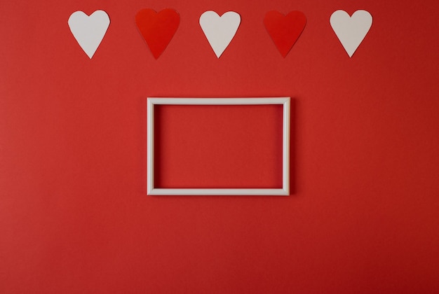 Coeurs de papier blanc et rouge sur fond rouge. Concept de la Saint-Valentin. Espace pour le texte. Mise à plat, vue de dessus.