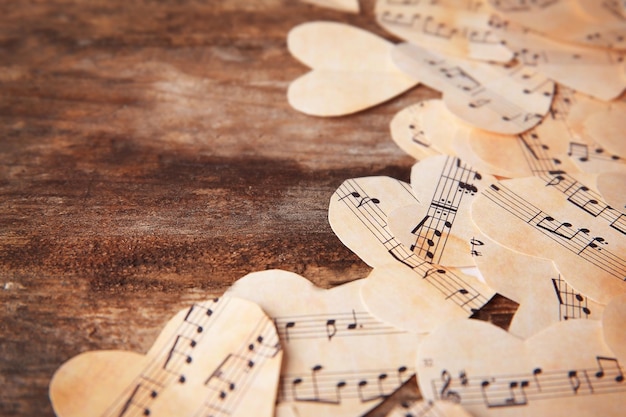 Coeurs de papier avec des notes de musique sur fond de bois