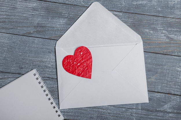 Coeurs de papier rouge avec enveloppe et papernote sur une surface en bois