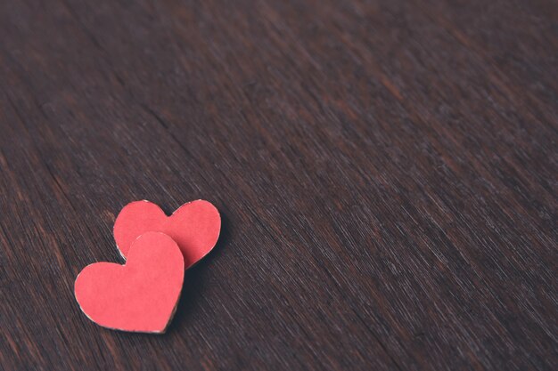 Coeurs en papier rouge sur une table en bois foncé