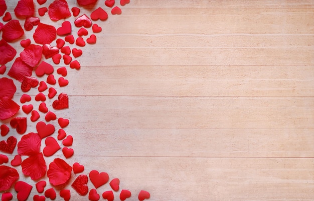 Coeurs et pétales de satin rouge sur une planche de bois Modèle de carte de voeux Mise à plat Copier l'espace