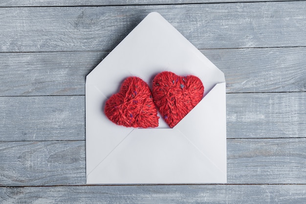 Coeurs rouges avec enveloppe sur une surface en bois