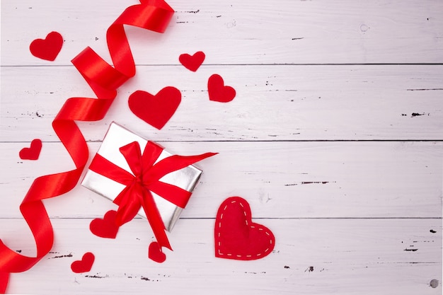 Coeurs rouges, ruban et cadeau sur fond en bois blanc. Vue de dessus, espace libre pour le texte. la Saint-Valentin, mon amour.