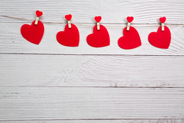 Coeurs rouges suspendus à une corde avec des pinces à linge sur un fond de bois avec une guirlande Saint Valentin photo de haute qualité