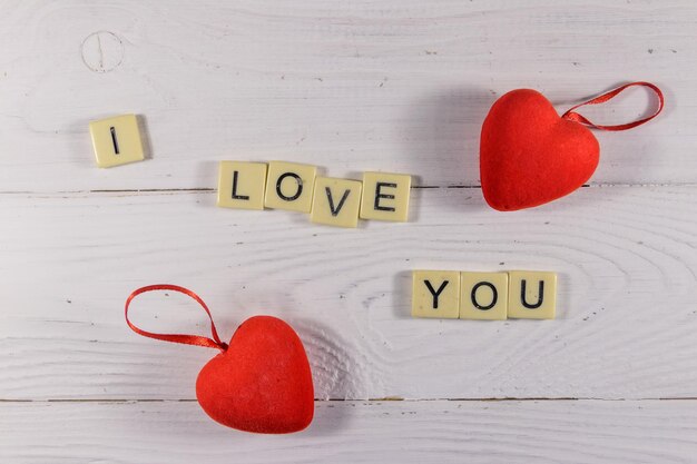 Coeurs rouges et texte "Je t'aime" sur fond de bois blanc. Vue de dessus