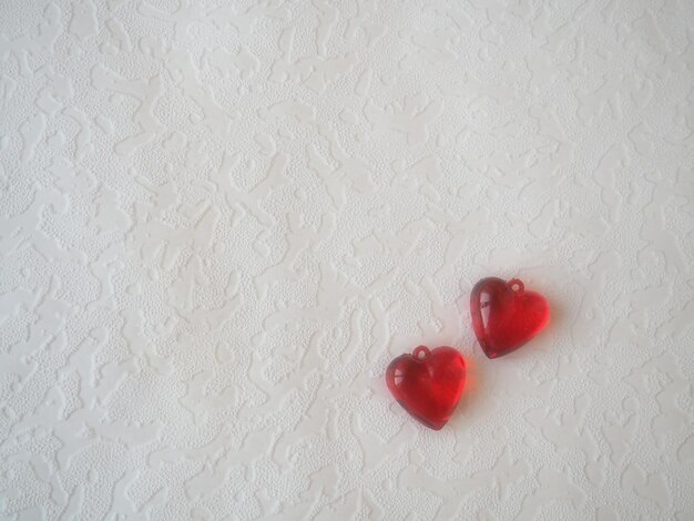 Coeurs de la Saint-Valentin. Coeurs transparents en plastique rouge. Carte de voeux avec fond blanc pour la saint valentin de vacances. Une expression d'amour. Copiez l'espace. Mise à plat. Fond blanc ondulé