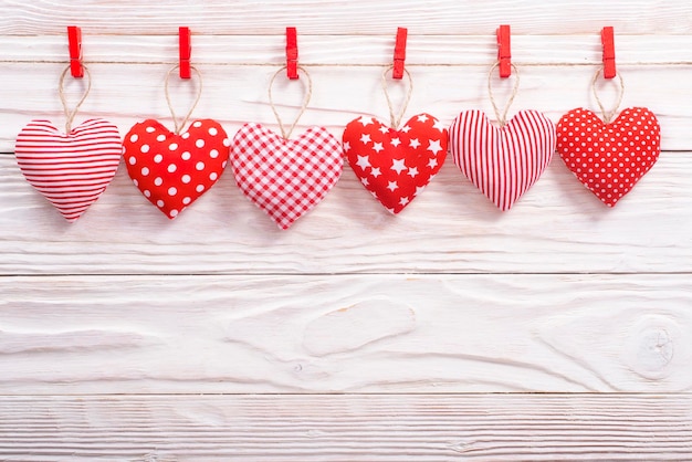 Coeurs de tissu de la Saint-Valentin pendus à la corde sur fond de bois blanc