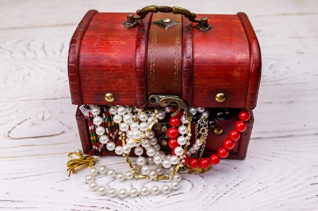 Coffre au trésor vintage plein de bijoux et d'accessoires sur fond de bois blanc