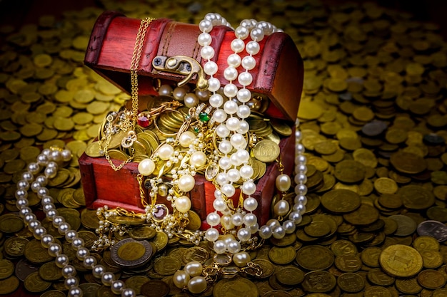 Coffre au trésor vintage rempli de pièces d'or et de bijoux sur fond de pièces d'or