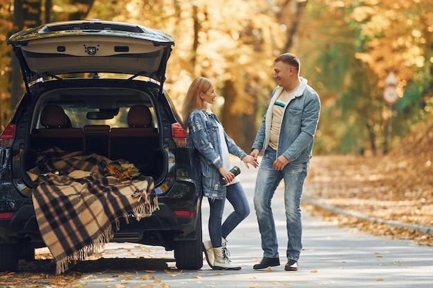 Coffre ouvert Couple debout sur la route dans le parc près de l'automobile