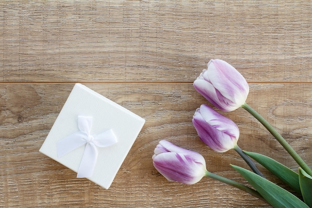 Coffret blanc avec de belles tulipes sur les planches de bois Concept d'offrir un cadeau en vacances