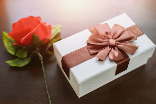 Coffret blanc et rose rouge sur table en bois