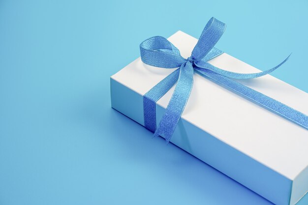 Coffret blanc avec ruban bleu sur fond bleu