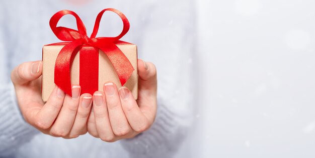 Coffret cadeau avec un arc rouge dans les mains des femmes