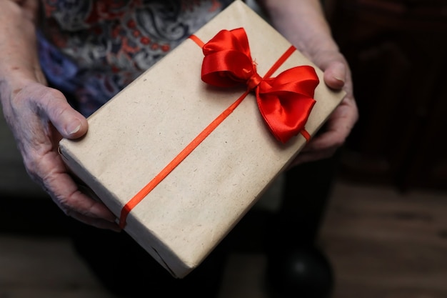 Coffret cadeau avec arc rouge en macro de mains de grand-mère